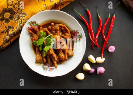 Pieds de poulet épicés au céleri, au piment, à l'oignon et à l'ail servis avec une assiette blanche sur la table Banque D'Images
