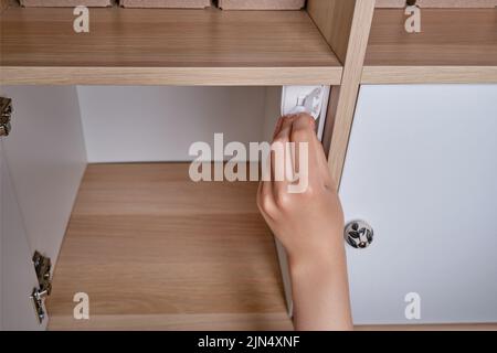 Installation d'une serrure magnétique à l'épreuve des enfants pour protéger les portes et les tiroirs des meubles de maison Banque D'Images