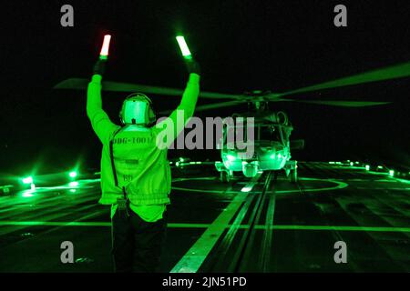 24 juillet 2022 - Océan Pacifique - Gunners Mate 3rd classe Jonathan Castillo signale qu'un hélicoptère MH-60s Sea Hawk atterrit sur le pont de vol du destroyer à missiles guidés de classe Zumwalt USS Michael Monsoor (DDG 1001) pendant la Rim du Pacifique (RIMPAC) 2022, 24 juillet. Vingt-six nations, 38 navires, trois sous-marins, plus de 170 avions et 25 000 membres du personnel participent au programme RIMPAC de 29 juin à 4 août dans et autour des îles hawaïennes et du sud de la Californie. Le plus grand exercice maritime international du monde, RIMPAC offre une occasion unique de formation tout en favorisant et en soutenant le coop Banque D'Images