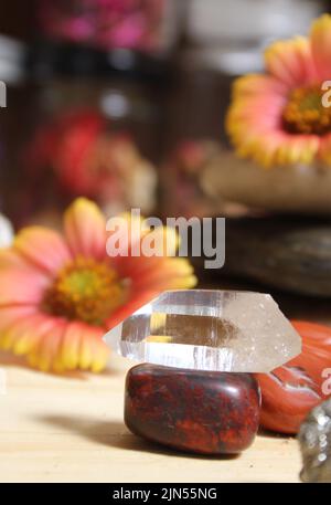 Quartz Crystal équilibré sur Bloodstone avec fleurs en arrière-plan Banque D'Images