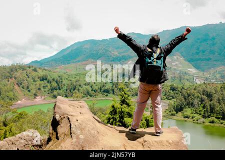 homme debout sur un rocher d'une falaise et profitant de la vue sur la nature du lac et de la montagne. symbole de la liberté' Banque D'Images