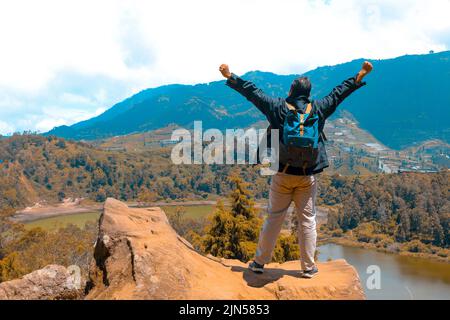 homme debout sur un rocher d'une falaise et profitant de la vue sur la nature du lac et de la montagne. symbole de la liberté' Banque D'Images