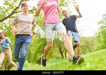 Groupe de jeunes qui s'exécutent sur un pré en été comme un entraînement ou un jeu de remise en forme Banque D'Images