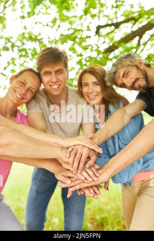 Groupe de jeunes qui se empilent les mains à l'événement d'équipe pour la communauté et la solidarité Banque D'Images