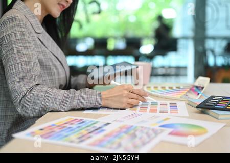 Vue rognée de la décoratrice d'intérieur féminine à l'aide d'une tablette numérique et utilisation de nuances de couleurs sur le lieu de travail Banque D'Images