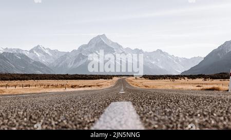 Vue sur les majestueuses Aoraki Mount Cook avec la route menant au Mont Cook Village. Prises au cours de l'hiver en Nouvelle-Zélande. Banque D'Images