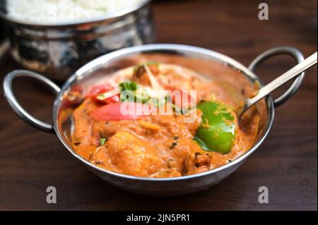 Plat de curry de poulet indien avec légumes dans un bol en acier servi avec du riz sur une table en bois brun foncé, espace de copie, foyer sélectionné, profondeur de f étroite Banque D'Images