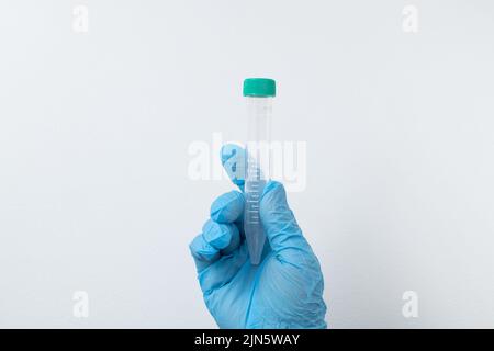 Tube à vide pour le prélèvement et les échantillons de sang dans des gants bleus pour laboratoire. Sur fond blanc Banque D'Images