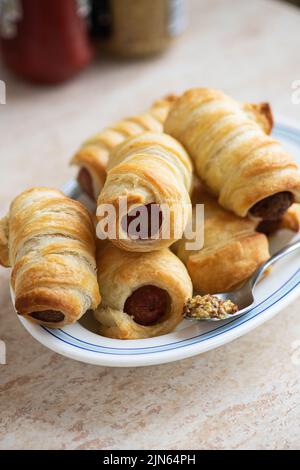 Cochons dans une couverture - petit rouleau de saucisse sur une assiette. Banque D'Images