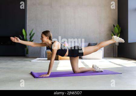 Femme sportive concentré durables est en train de faire l'élaboration à la maison et faisant partie de l'avant de son ordinateur portable, le port de vêtements de sport Banque D'Images