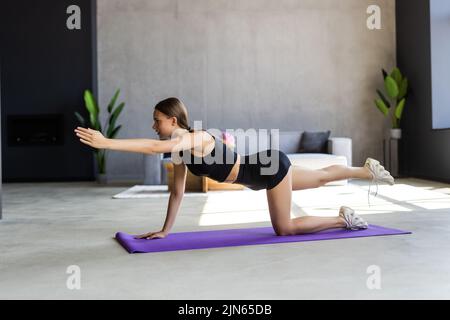 Femme sportive concentré durables est en train de faire l'élaboration à la maison et faisant partie de l'avant de son ordinateur portable, le port de vêtements de sport Banque D'Images