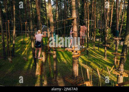 Une femme surmonte un obstacle dans une ville de corde. Une femme dans un parc de corde de forêt. Banque D'Images