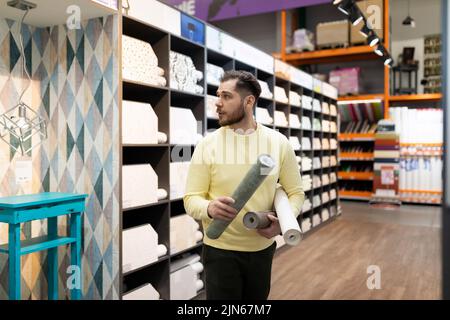 client satisfait à côté d'un rack avec papier peint en papier pour coller les murs Banque D'Images