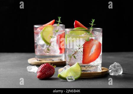 Cocktail mojito aux fraises fraîches. Deux verres avec soda aux fraises fraîches d'été avec fraise, glaçons et citron vert, décoré de thym foncé Banque D'Images