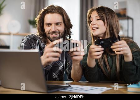 Jeux, divertissement, famille, concept de loisirs. Gros plan de la jeune famille caucasienne, tenant des joysticks et profitant de leur temps libre jouant de nouveaux jeux à la maison. Banque D'Images