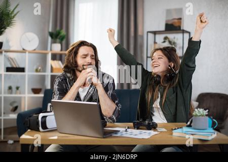 Jeux, divertissement, famille, concept de loisirs. Gros plan de la jeune famille caucasienne, tenant des joysticks et profitant de leur temps libre jouant de nouveaux jeux à la maison. La femme qui gagne de l'homme. Banque D'Images