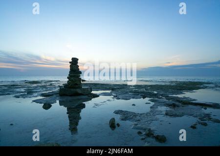 Les pierres empilées les unes sur les autres à la plage contre le coucher du soleil Banque D'Images