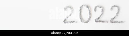 Baner Happy New Year 2022 écrit avec du papier d'aluminium et de la pluie du nouvel an sur un fond blanc isolé.Bonne année salutations Banque D'Images