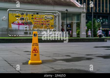 Un panneau attention sol mouillé à Raffles place, Singapour. Banque D'Images