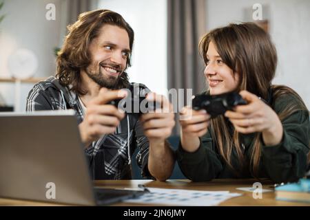 Jeux, divertissement, famille, concept de loisirs. Gros plan de la jeune famille caucasienne, tenant des joysticks et profitant de leur temps libre jouant de nouveaux jeux à la maison. Banque D'Images