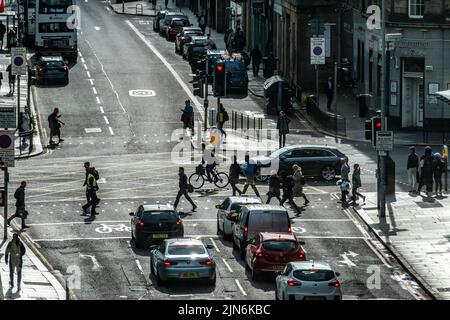 Piétons et cyclistes en silhouette traversant une rue animée à Édimbourg Banque D'Images