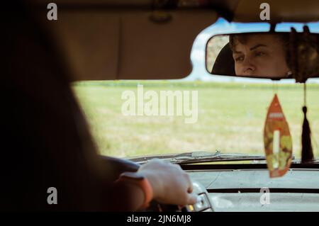 Femme regarde avec soin dans le miroir de voiture Banque D'Images