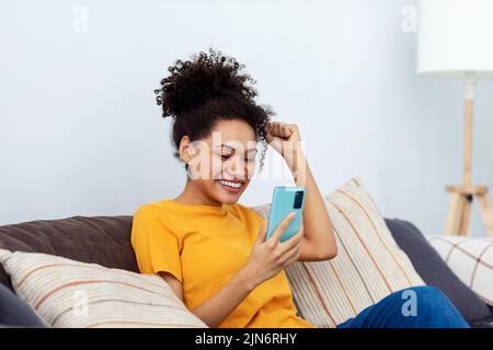 Une femme excitée a reçu un bon message sur le téléphone mobile heureux avec de grandes nouvelles Banque D'Images