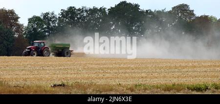 Berlin, Allemagne. 09th août 2022. Un agriculteur répand de l'engrais sur un champ de céréales moissonné près de Berlin, traînant derrière lui un nuage dense de poussière. Selon les météorologues, on ne s'attend pas à de pluie dans les jours à venir et les températures continueront d'augmenter. Credit: Wolfgang Kumm/dpa/Alay Live News Banque D'Images