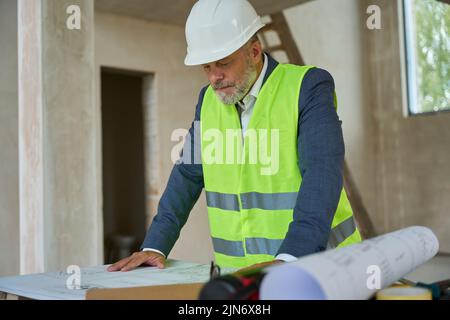 Le gilet de construction de contremaître regarde le dessin sur la table Banque D'Images