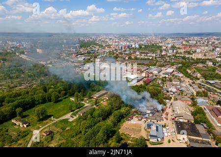 Vue aérienne des pompiers l'extinction a ruiné le bâtiment sur le feu avec le toit écrasé et la montée de fumée sombre Banque D'Images