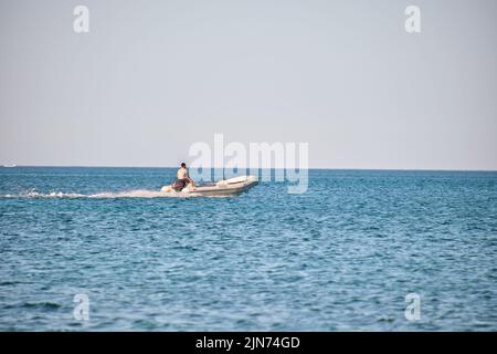 Paysage de mer avec surface ondulée d'eau de mer bleue avec hors-bord blanc nageant rapidement sur des vagues calmes Banque D'Images