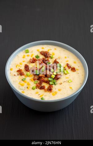 Chaudrée de maïs maison avec bacon dans un bol sur fond noir, vue latérale. Banque D'Images