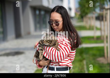 Jeune femme tenant le chat tabby dans ses bras à l'extérieur. Banque D'Images