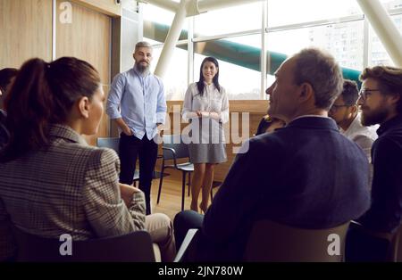 Les managers masculins et féminins communiquent avec le personnel assis autour d'eux en cercle sur les chaises. Banque D'Images