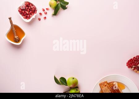 Roch Hachana. Pot de miel, nid d'abeille, pomme et grenade sur fond rose simple. Carte de vœux juive pour le nouvel an. Rosh Hashanah Holiday att Banque D'Images