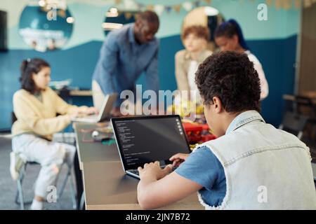 Vue arrière d'un garçon utilisant un ordinateur portable dans la classe d'ingénierie et de robots de programmation, espace de copie Banque D'Images