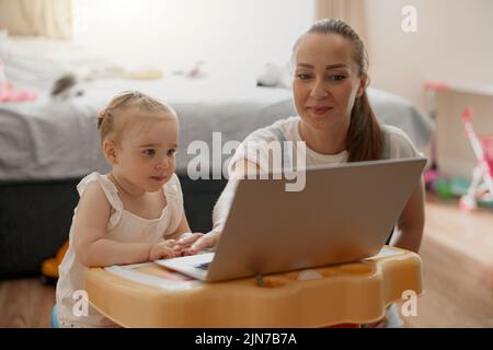 Bonne mère et fille de passer du temps libre et regarder des dessins animés sur ordinateur portable à la maison Banque D'Images