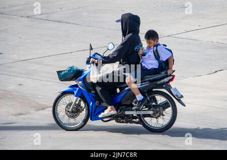 SAMUT PRAKAN, THAÏLANDE, JUIN 09 2022, Une femme à bord d'une moto avec un garçon en uniforme scolaire Banque D'Images
