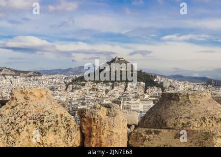 La chapelle Georgios blanchie à la chaux perchée au sommet de la colline de Lykavittos à Athènes, vue de derrière les murs de roche de l'Acropole Banque D'Images