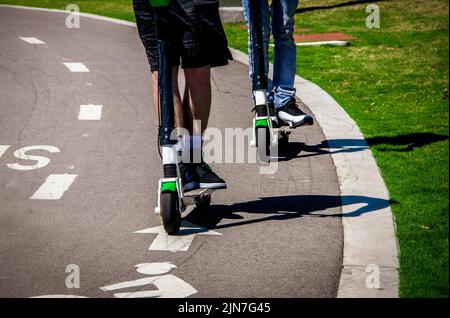 Deux garçons sur des scooters motorisés - écourté aux jambes - sur la piste en parc en été Banque D'Images