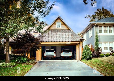 Garage pour deux voitures ouvert avec deux SUVS blancs garés à l'intérieur le jour de l'automne Banque D'Images