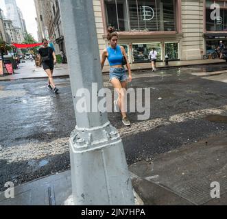 Les gens font face à une descente torrentielle dans le quartier de Nomad à New York le dimanche, 7 août 2022. Une chaleur et une humidité sans pitié sont attendues cette semaine à mesure que les températures montent au milieu des années 90, avec une humidité sueur ajoutée au mélange soupy. (© Richard B. Levine) Banque D'Images