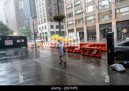 Les gens font face à une descente torrentielle dans le quartier de Nomad à New York le dimanche, 7 août 2022. Une chaleur et une humidité sans pitié sont attendues cette semaine à mesure que les températures montent au milieu des années 90, avec une humidité sueur ajoutée au mélange soupy. (© Richard B. Levine) Banque D'Images