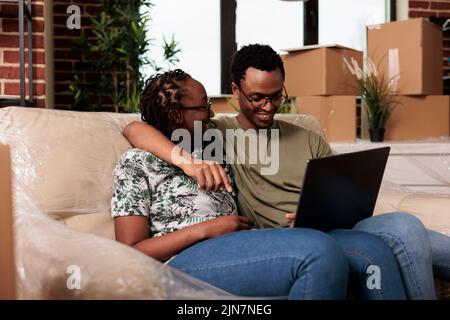 Heureux couple marié trouver des meubles sur le site Web en ligne, shopping sur ordinateur portable pour décorer appartement loué. Acheter des décorations sur le navigateur Internet après avoir déplacé dans la nouvelle propriété de ménage. Banque D'Images