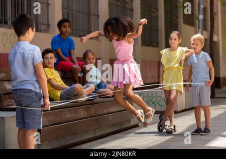 Jeu de saut de petite fille péruvienne par le groupe de caoutchouc avec des amis européens Banque D'Images