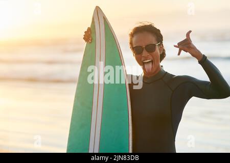 Les jours passés à la plage sont toujours les meilleurs. Portrait d'une belle jeune femme surfeuse posant avec sa planche de surf à la plage. Banque D'Images