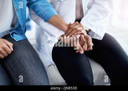 Je suis ici pour vous aider. Un médecin tient la main avec un patient dans sa salle de consultation. Banque D'Images