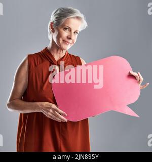 Le système IVE a reçu un message pour la jeune génération. Portrait d'une femme mûre tenant une bulle de la parole sur un fond gris. Banque D'Images