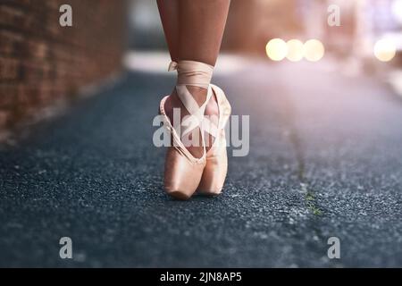 Le cœur d'une danseuse se trouve à ses pieds. Une danseuse de ballet debout sur des orteils contre un fond urbain. Banque D'Images