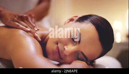 C'est une belle jeune femme qui profite d'un massage du dos dans un spa de beauté. Banque D'Images